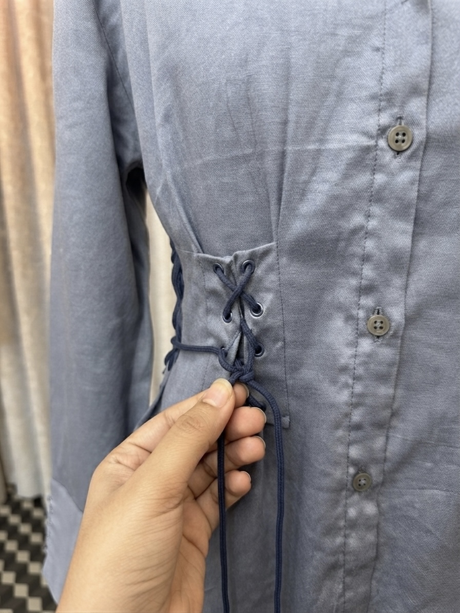 Tying the corset-style lace detail on a grey cotton shirt
